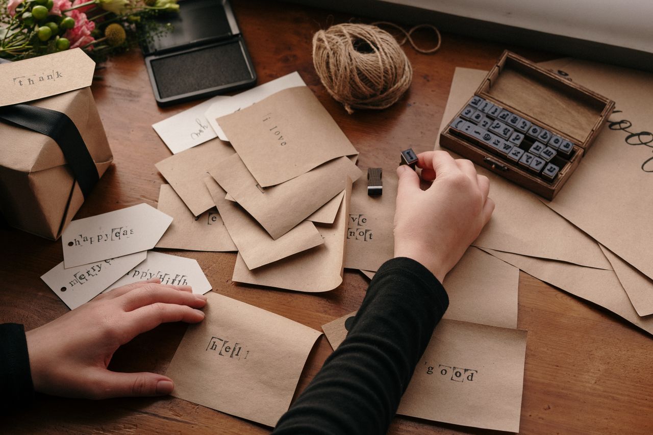 services-01 A person stamping envelopes with letters for handmade cards, showcasing creativity and craftsmanship.